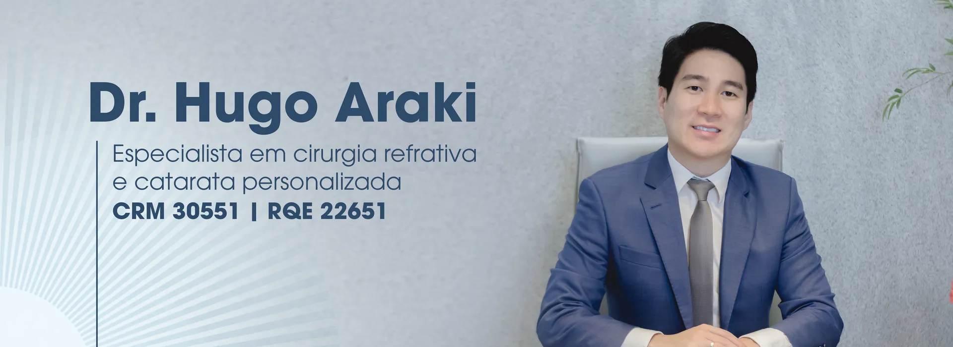 Dr. Hugo Araki sentado em seu consultório: especialista em cirurgia refrativa e catarata personalizada, CRM 30551, RQE 22651.